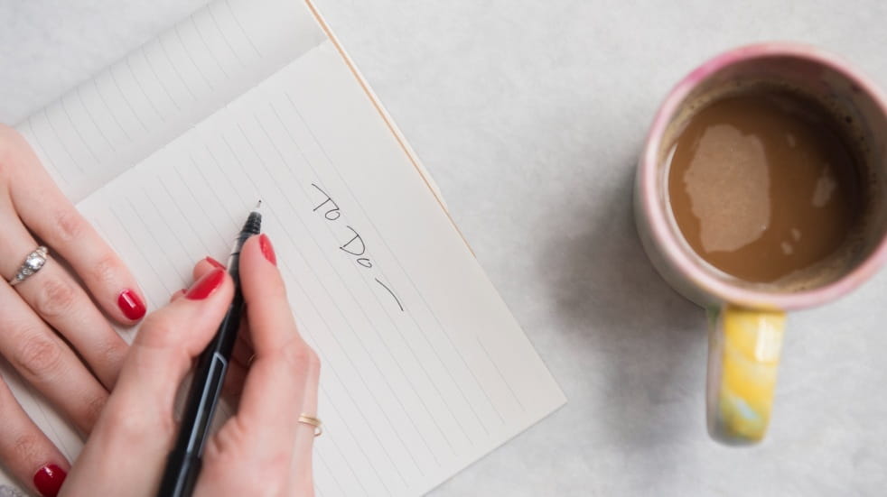 woman writing to do list with coffee